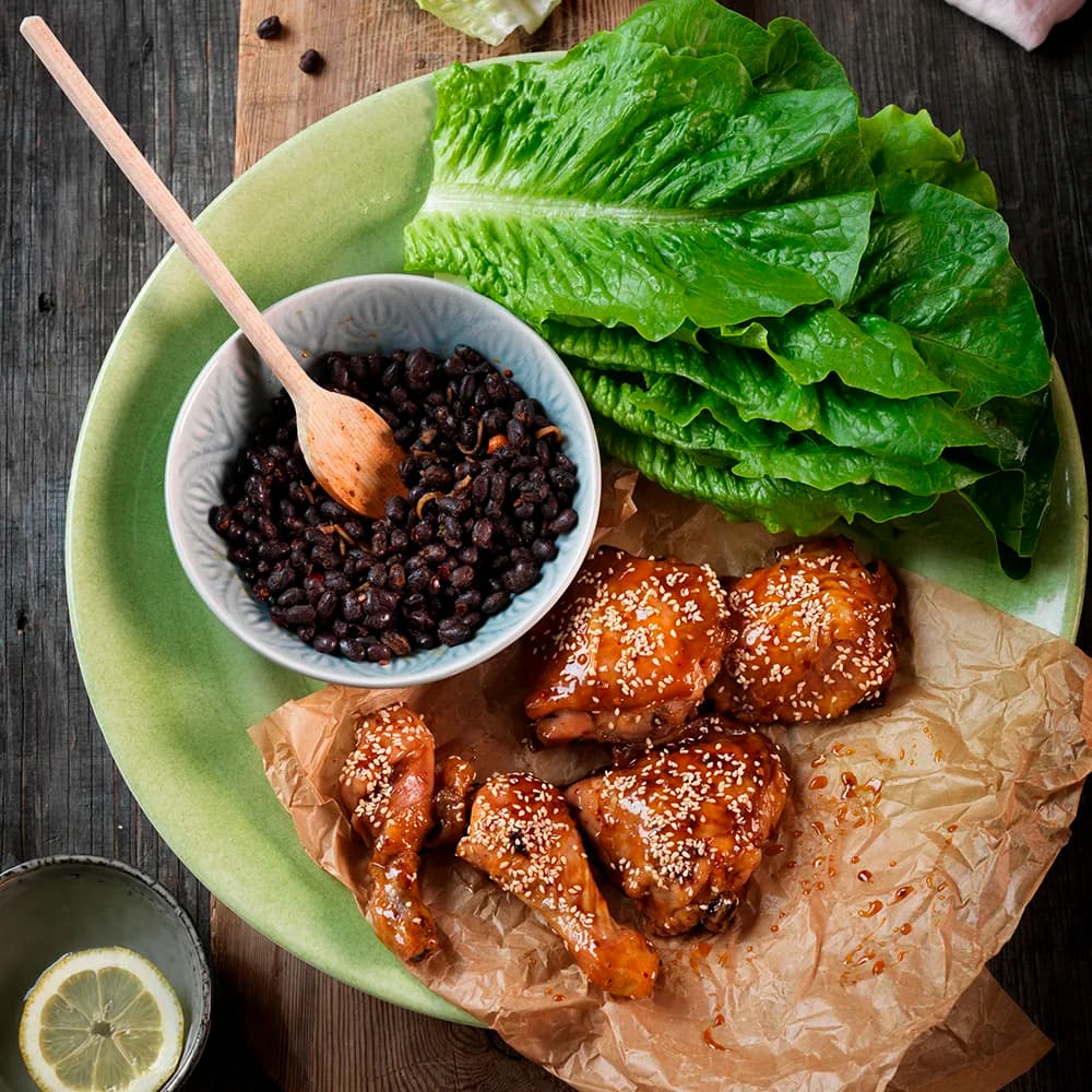 Sticky drumsticks med svarta bönor i salladsblad